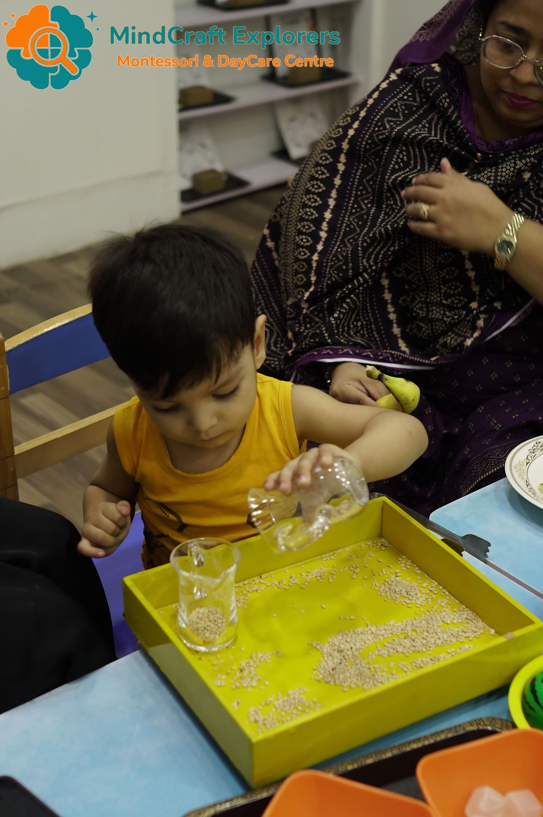 A toddler pouring grains into a tray