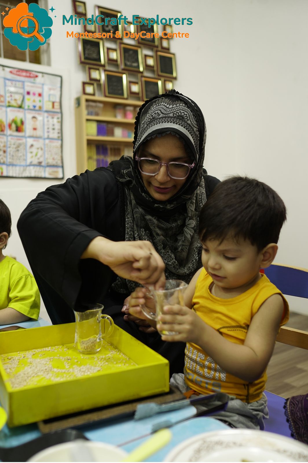 A teacher helping a boy pour from a jug