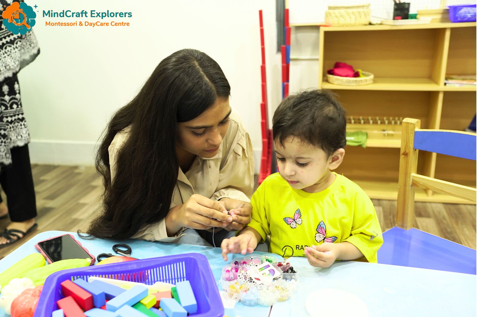A teacher guiding a toddler through a hands-on activity
